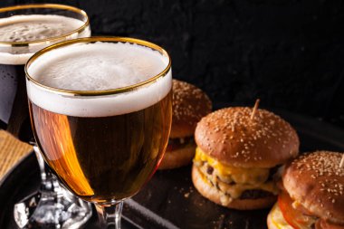 Bardakta soğuk bira ve sulu büyük hamburger şeklinde atıştırmalık. Fast food.