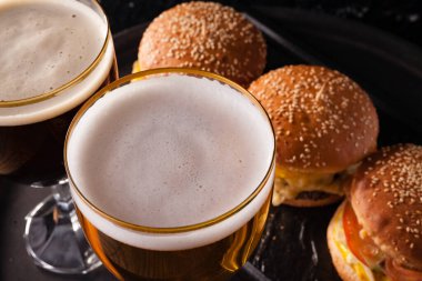 Bardakta soğuk bira ve sulu büyük hamburger şeklinde atıştırmalık. Fast food.