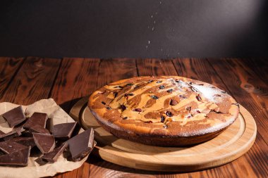 Üzerine krema serpiştirilmiş çikolatalı pasta. Tahta masadaki çikolatalı pasta..