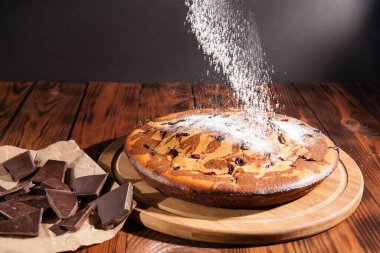 Üzerine krema serpiştirilmiş çikolatalı pasta. Tahta masadaki çikolatalı pasta..