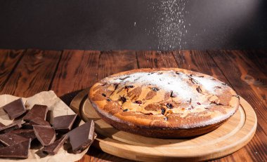 Üzerine krema serpiştirilmiş çikolatalı pasta. Tahta masadaki çikolatalı pasta..