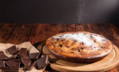 Üzerine krema serpiştirilmiş çikolatalı pasta. Tahta masadaki çikolatalı pasta..