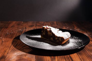Üzerine krema serpiştirilmiş çikolatalı pasta. Tahta masadaki çikolatalı pasta..
