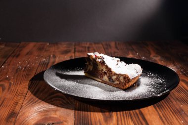 Üzerine krema serpiştirilmiş çikolatalı pasta. Tahta masadaki çikolatalı pasta..