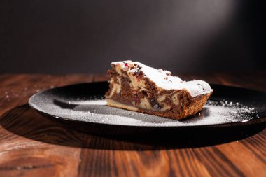 Üzerine krema serpiştirilmiş çikolatalı pasta. Tahta masadaki çikolatalı pasta..