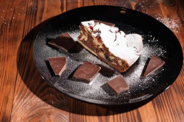 Üzerine krema serpiştirilmiş çikolatalı pasta. Tahta masadaki çikolatalı pasta..