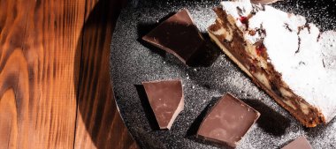 Üzerine krema serpiştirilmiş çikolatalı pasta. Tahta masadaki çikolatalı pasta..