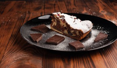 Üzerine krema serpiştirilmiş çikolatalı pasta. Tahta masadaki çikolatalı pasta..