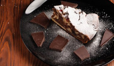 Üzerine krema serpiştirilmiş çikolatalı pasta. Tahta masadaki çikolatalı pasta..