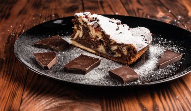 Üzerine krema serpiştirilmiş çikolatalı pasta. Tahta masadaki çikolatalı pasta..