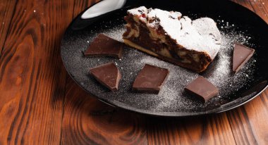 Üzerine krema serpiştirilmiş çikolatalı pasta. Tahta masadaki çikolatalı pasta..