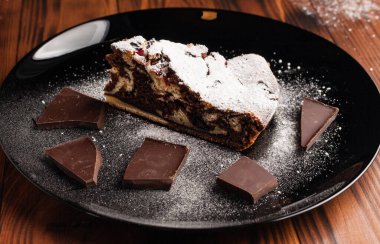 Üzerine krema serpiştirilmiş çikolatalı pasta. Tahta masadaki çikolatalı pasta..