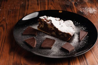 Üzerine krema serpiştirilmiş çikolatalı pasta. Tahta masadaki çikolatalı pasta..