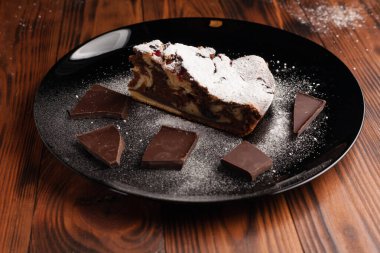 Üzerine krema serpiştirilmiş çikolatalı pasta. Tahta masadaki çikolatalı pasta..