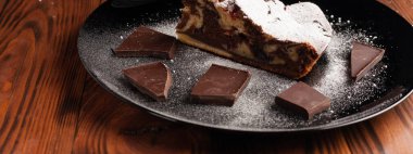 Üzerine krema serpiştirilmiş çikolatalı pasta. Tahta masadaki çikolatalı pasta..