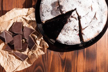 Üzerine krema serpiştirilmiş çikolatalı pasta. Tahta masadaki çikolatalı pasta..