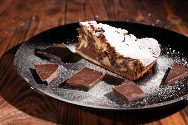 Üzerine krema serpiştirilmiş çikolatalı pasta. Tahta masadaki çikolatalı pasta..