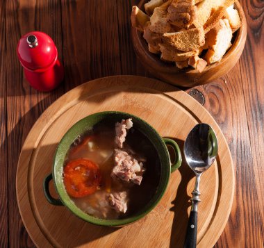 Köy eti çorbası / çorba üzerine yeşil soğan serpiştirilmiş ahşap bir masada kraker.