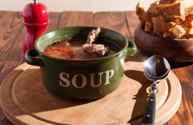 Köy eti çorbası / çorba üzerine yeşil soğan serpiştirilmiş ahşap bir masada kraker.