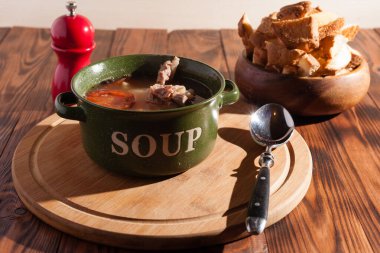 Köy eti çorbası / çorba üzerine yeşil soğan serpiştirilmiş ahşap bir masada kraker.