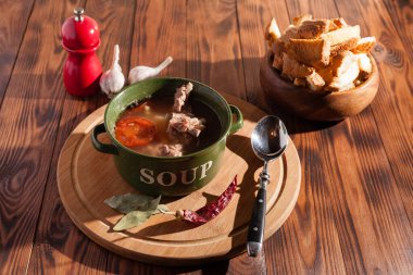 Köy eti çorbası / çorba üzerine yeşil soğan serpiştirilmiş ahşap bir masada kraker.