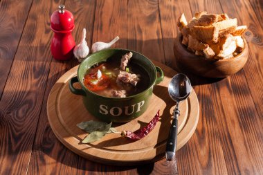 Köy eti çorbası / çorba üzerine yeşil soğan serpiştirilmiş ahşap bir masada kraker.