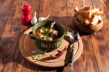 Köy eti çorbası / çorba üzerine yeşil soğan serpiştirilmiş ahşap bir masada kraker.