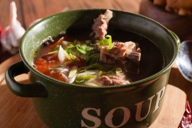 Köy eti çorbası / çorba üzerine yeşil soğan serpiştirilmiş ahşap bir masada kraker.