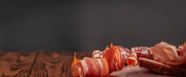 Tahta kesme tahtasının üzerinde çeşitli mezeler. Sosis, jambon, pastırma, tütsülenmiş et. Boş alanı olan et ürünlerinin stok fotoğrafı.