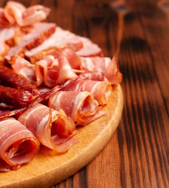 Tahta kesme tahtasının üzerinde çeşitli mezeler. Sosis, jambon, pastırma, tütsülenmiş et. Boş alanı olan et ürünlerinin stok fotoğrafı.