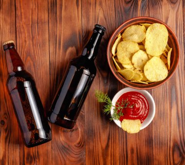 Şişede bira, kuru tuzlu abur cubur, ahşap bir masada boş yer var..