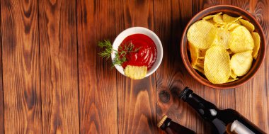 Şişede bira, kuru tuzlu abur cubur, ahşap bir masada boş yer var..