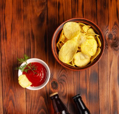 Şişede bira, kuru tuzlu abur cubur, ahşap bir masada boş yer var..