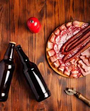 Et ürünleri ve şişe bira şeklinde atıştırmalıklar. Pastırma, salam, jambon ve av sosisi şeklinde aperatif. Stok fotoğraf birası ve ahşap bir masada atıştırmalık.