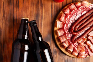 Et ürünleri ve şişe bira şeklinde atıştırmalıklar. Pastırma, salam, jambon ve av sosisi şeklinde aperatif. Stok fotoğraf birası ve ahşap bir masada atıştırmalık.