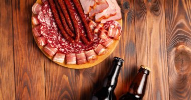 Et ürünleri ve şişe bira şeklinde atıştırmalıklar. Pastırma, salam, jambon ve av sosisi şeklinde aperatif. Stok fotoğraf birası ve ahşap bir masada atıştırmalık.