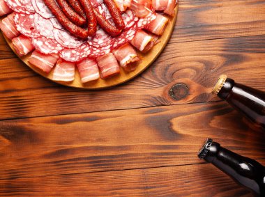 Et ürünleri ve şişe bira şeklinde atıştırmalıklar. Pastırma, salam, jambon ve av sosisi şeklinde aperatif. Stok fotoğraf birası ve ahşap bir masada atıştırmalık.