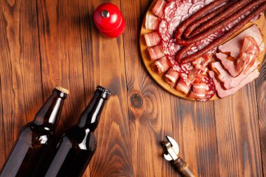 Et ürünleri ve şişe bira şeklinde atıştırmalıklar. Pastırma, salam, jambon ve av sosisi şeklinde aperatif. Stok fotoğraf birası ve ahşap bir masada atıştırmalık.
