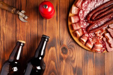 Et ürünleri ve şişe bira şeklinde atıştırmalıklar. Pastırma, salam, jambon ve av sosisi şeklinde aperatif. Stok fotoğraf birası ve ahşap bir masada atıştırmalık.
