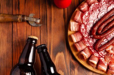 Et ürünleri ve şişe bira şeklinde atıştırmalıklar. Pastırma, salam, jambon ve av sosisi şeklinde aperatif. Stok fotoğraf birası ve ahşap bir masada atıştırmalık.