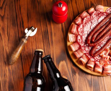 Et ürünleri ve şişe bira şeklinde atıştırmalıklar. Pastırma, salam, jambon ve av sosisi şeklinde aperatif. Stok fotoğraf birası ve ahşap bir masada atıştırmalık.