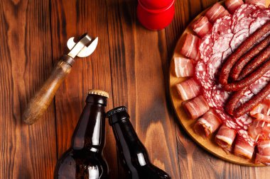 Et ürünleri ve şişe bira şeklinde atıştırmalıklar. Pastırma, salam, jambon ve av sosisi şeklinde aperatif. Stok fotoğraf birası ve ahşap bir masada atıştırmalık.