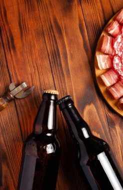 Et ürünleri ve şişe bira şeklinde atıştırmalıklar. Pastırma, salam, jambon ve av sosisi şeklinde aperatif. Stok fotoğraf birası ve ahşap bir masada atıştırmalık.