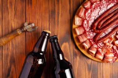 Et ürünleri ve şişe bira şeklinde atıştırmalıklar. Pastırma, salam, jambon ve av sosisi şeklinde aperatif. Stok fotoğraf birası ve ahşap bir masada atıştırmalık.
