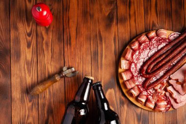 Et ürünleri ve şişe bira şeklinde atıştırmalıklar. Pastırma, salam, jambon ve av sosisi şeklinde aperatif. Stok fotoğraf birası ve ahşap bir masada atıştırmalık.