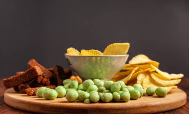 Tahta bir tahtanın üzerinde çeşitli kuru çerezler. Cips, fıstık, kızarmış ekmek, wasabi..