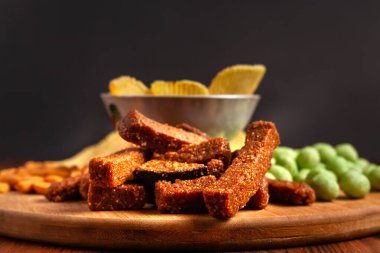 Tahta bir tahtanın üzerinde çeşitli kuru çerezler. Cips, fıstık, kızarmış ekmek, wasabi..