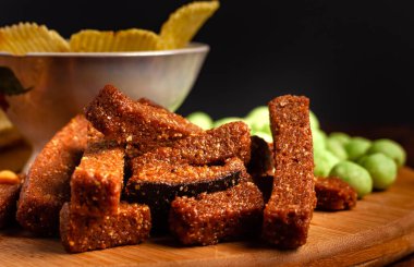 Tahta bir tahtanın üzerinde çeşitli kuru çerezler. Cips, fıstık, kızarmış ekmek, wasabi..