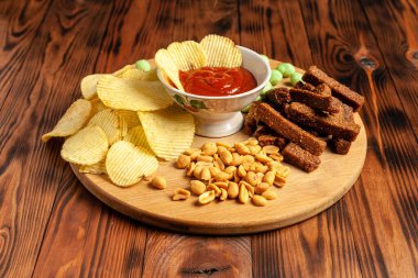 Tahta bir tahtanın üzerinde çeşitli kuru çerezler. Cips, fıstık, kızarmış ekmek, wasabi..