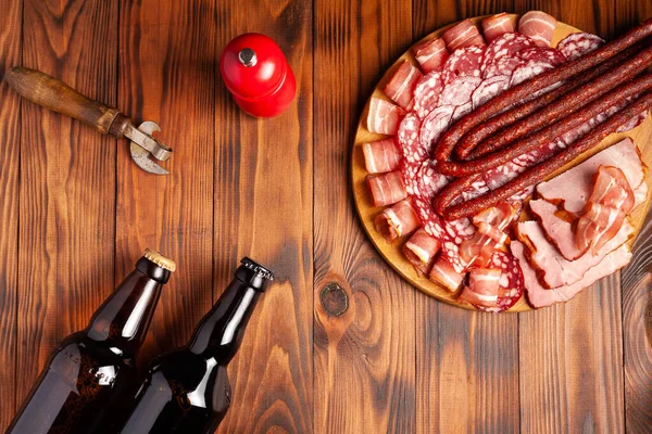 Et ürünleri ve şişe bira şeklinde atıştırmalıklar. Pastırma, salam, jambon ve av sosisi şeklinde aperatif. Stok fotoğraf birası ve ahşap bir masada atıştırmalık.